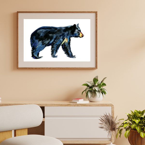 Framed artwork of a bear on a wall above a desk with plants.